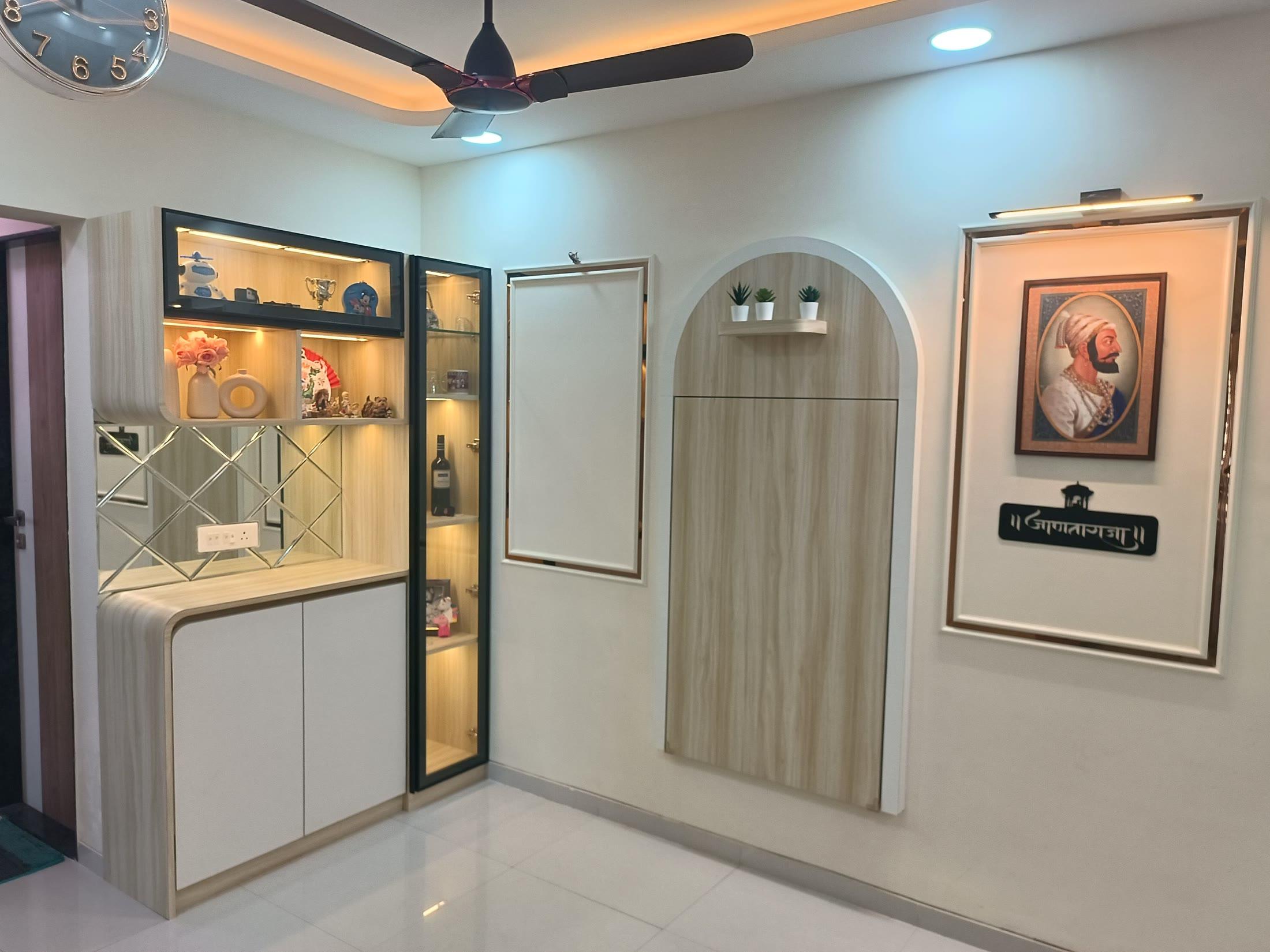 Living and dining wall with a lit display unit, arched wooden niche and framed art