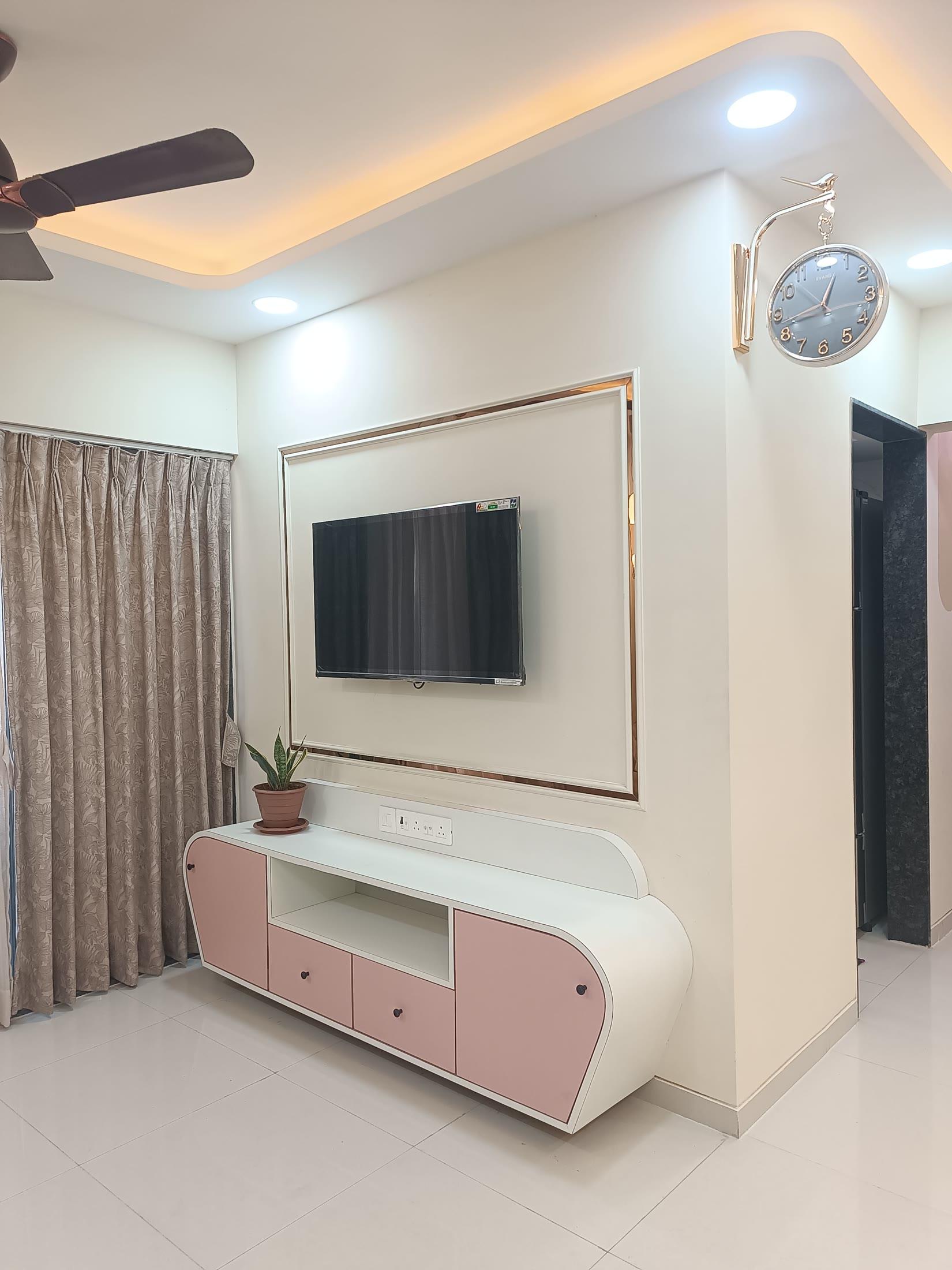 Living room with a wall-mounted television, wall clock and cove-lit ceiling