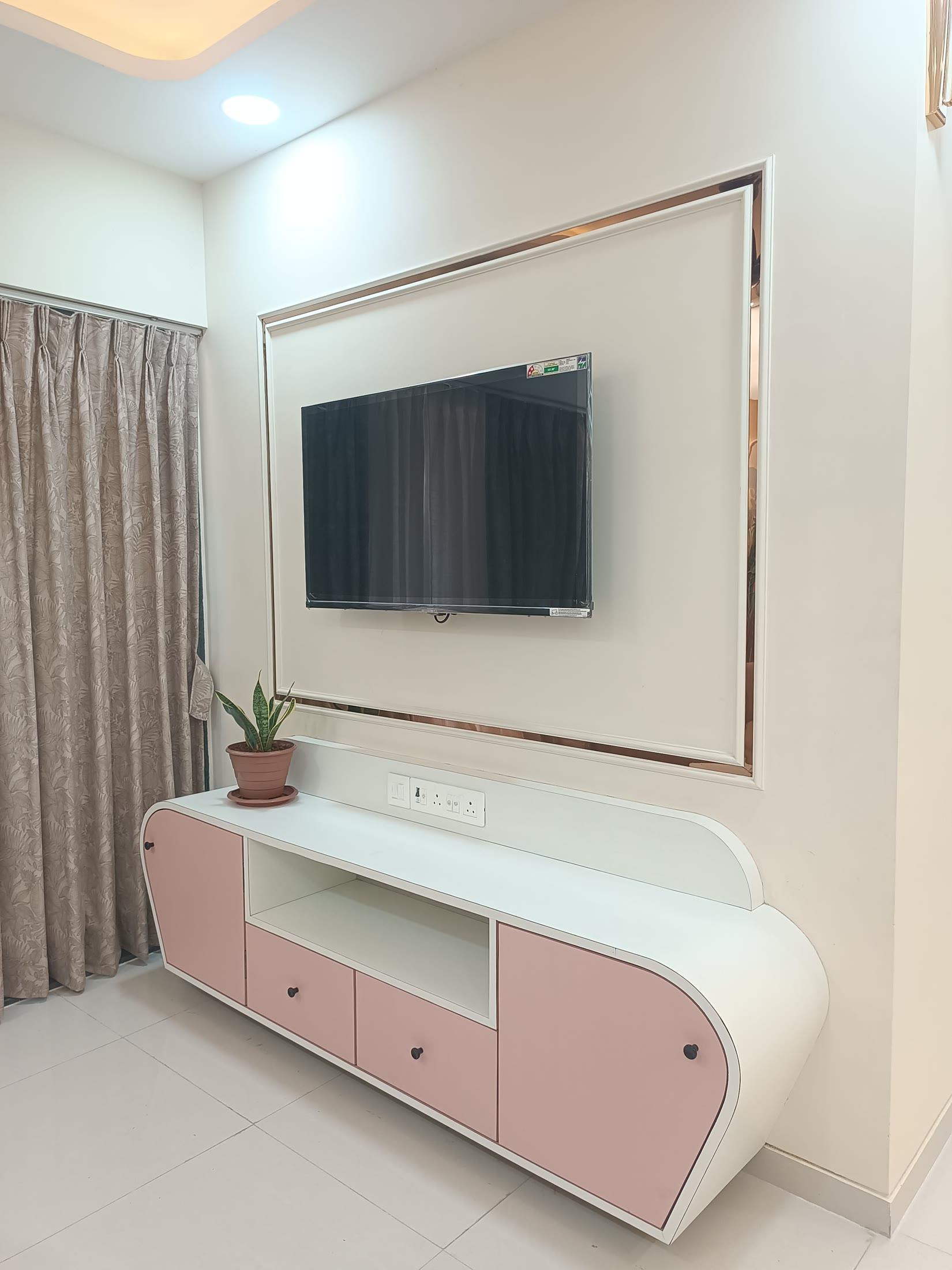Television unit with a gold-framed back panel and a curved white and blush lowboard