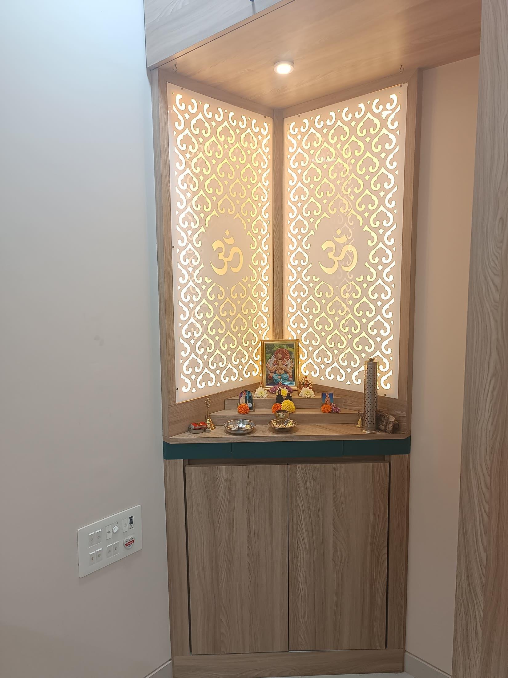 Pooja unit with a backlit jali screen above a wooden base cabinet