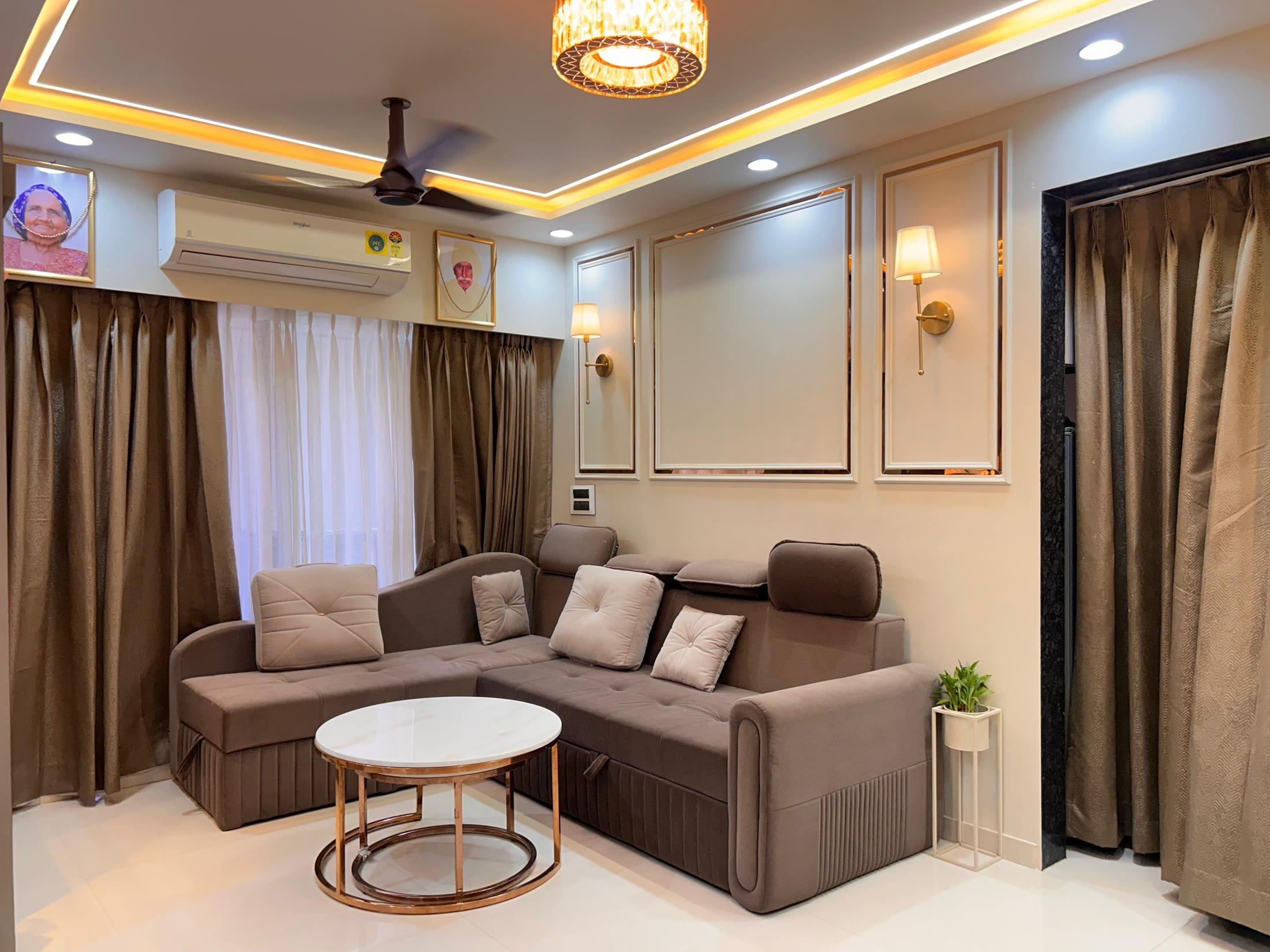 Living room with an L-shaped sofa, moulded wall frames and a crystal chandelier