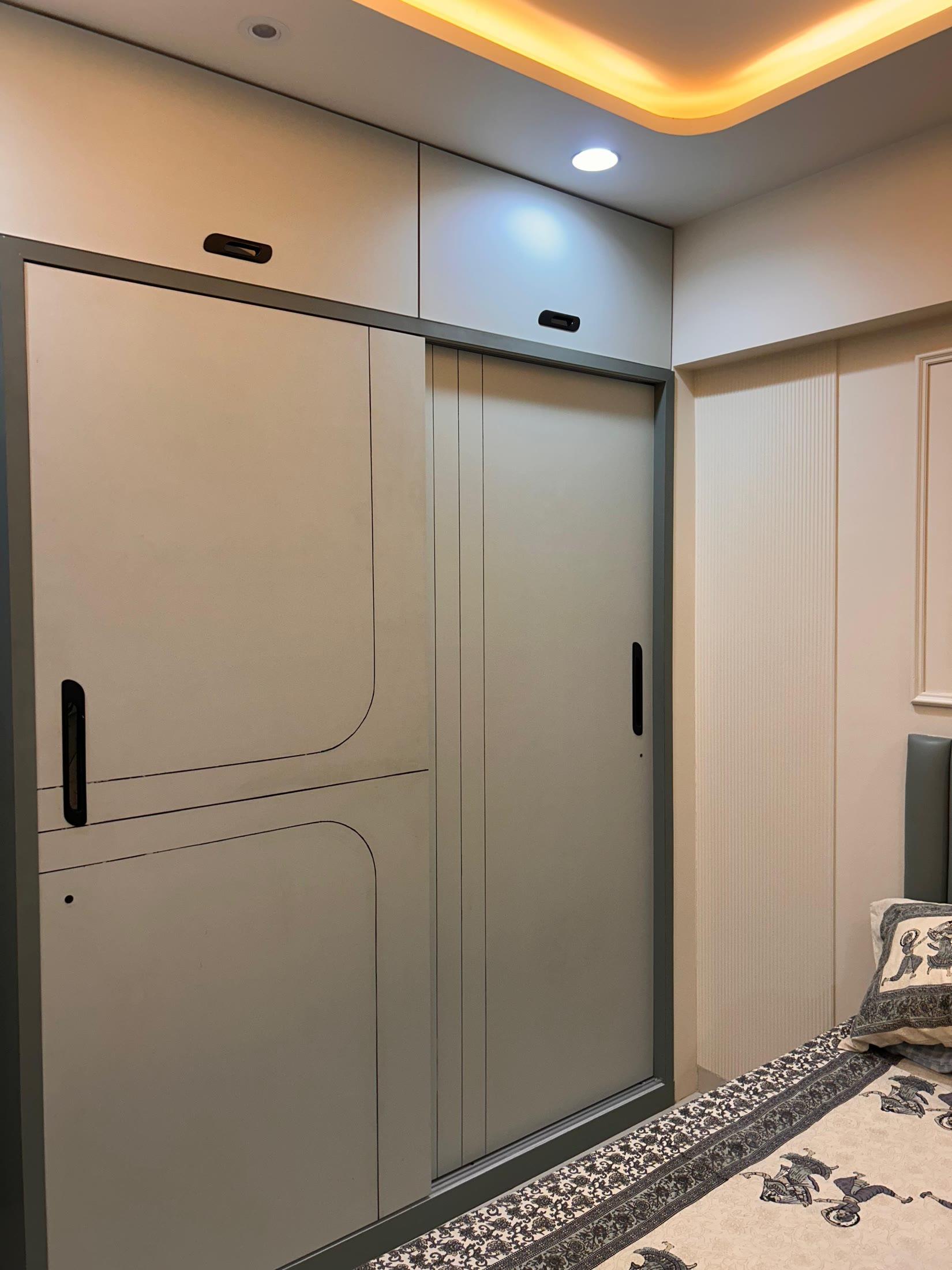 Sliding wardrobe in sage and grey shutters under a cove ceiling