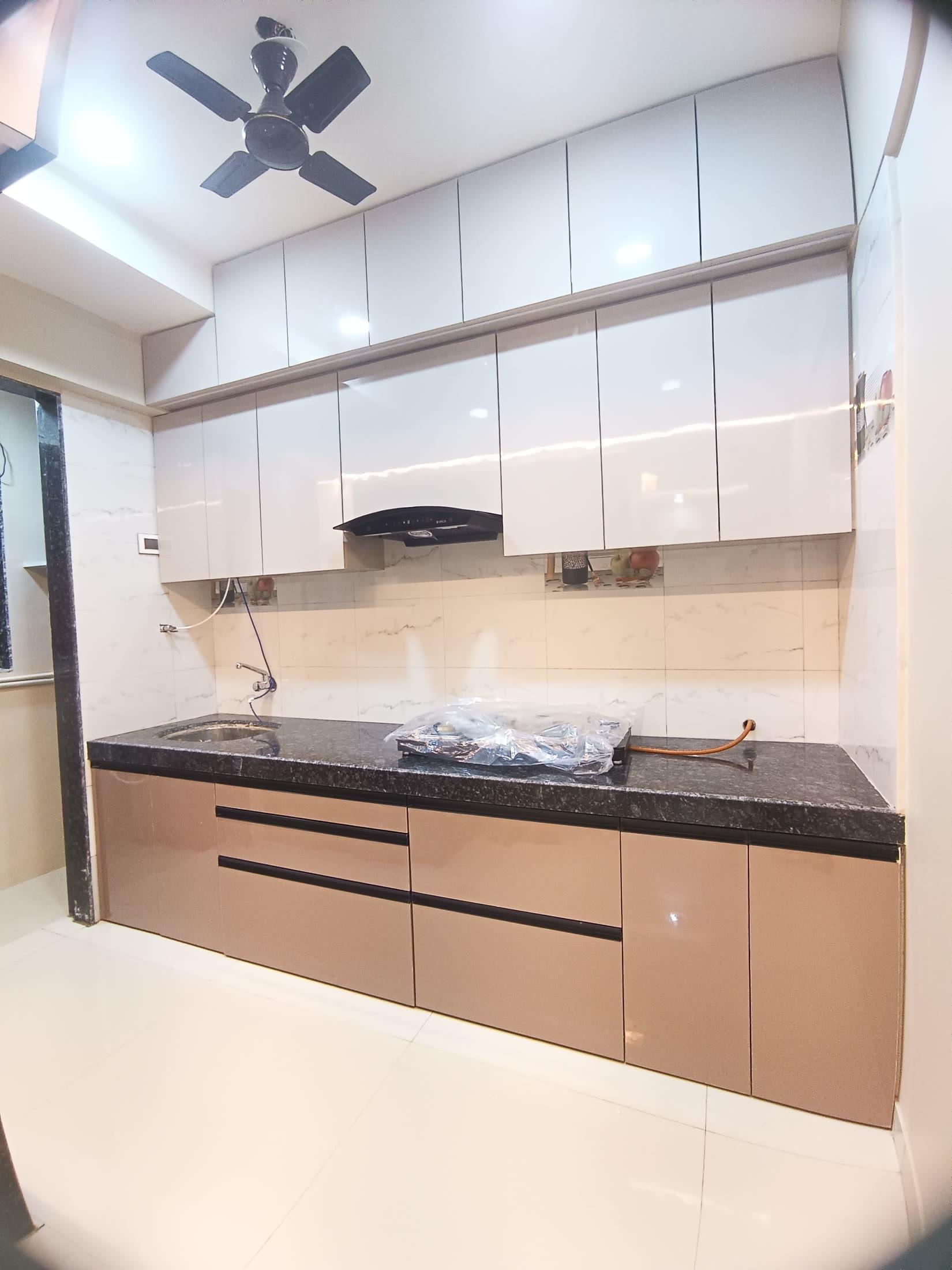 Modular kitchen with glossy overhead units and a black granite counter
