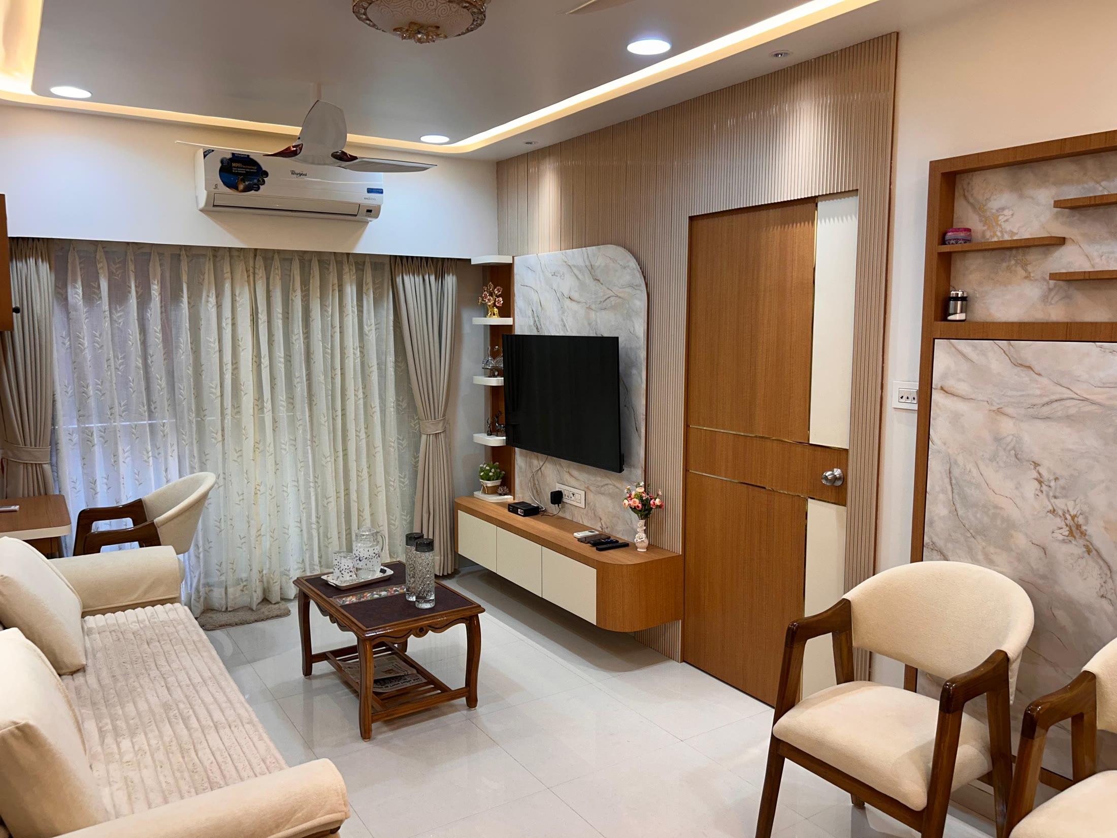 Living room with a marble media wall in teak trim, cream tub chairs and a daybed