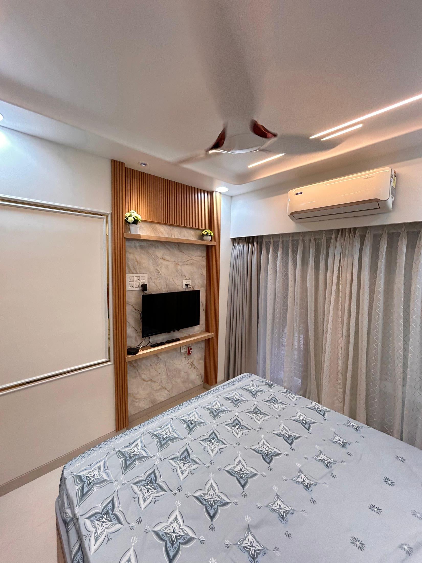 Bedroom media panel under a cove ceiling with linear lighting