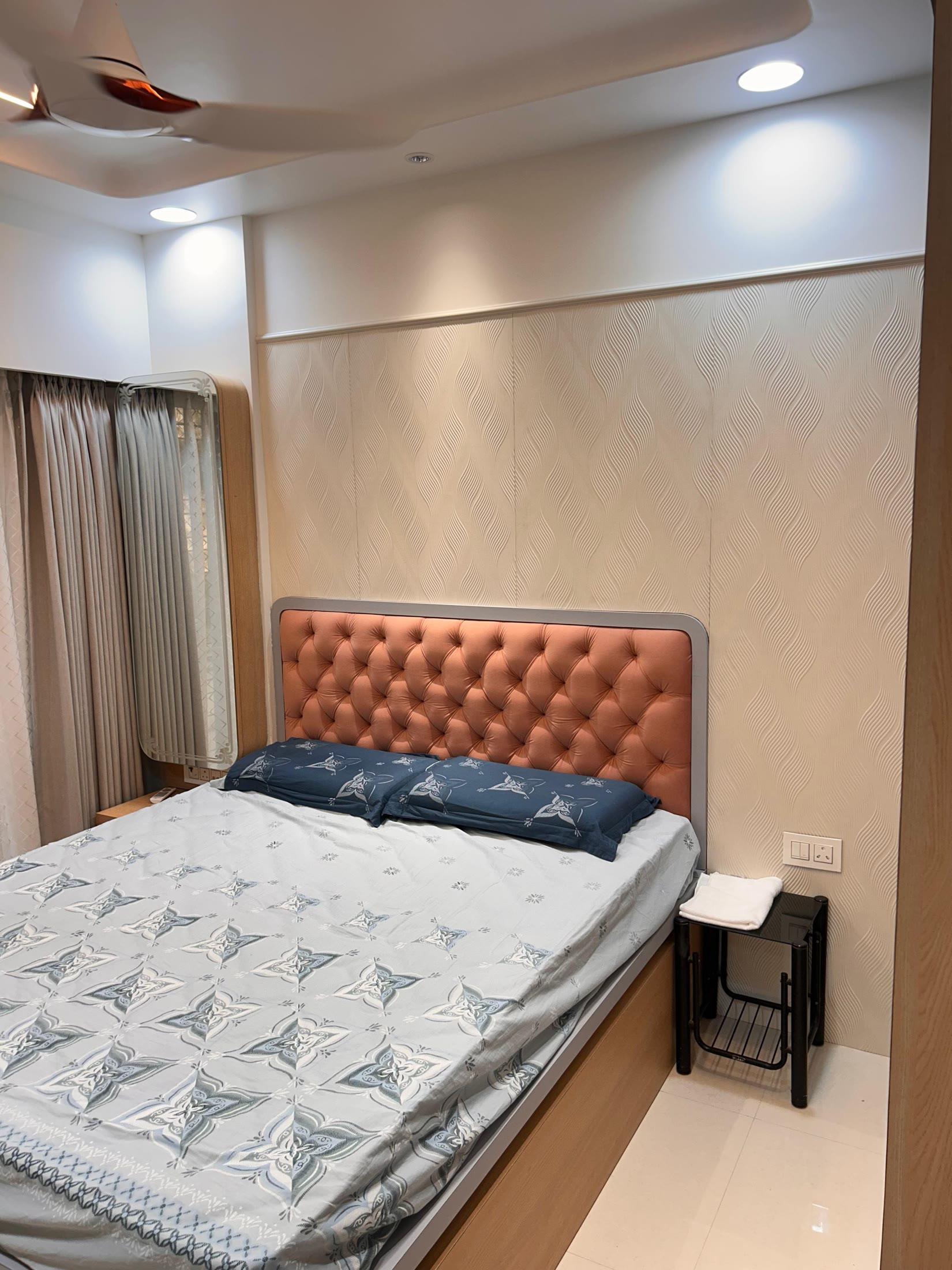 Bedroom with the tufted headboard against a textured wall finish